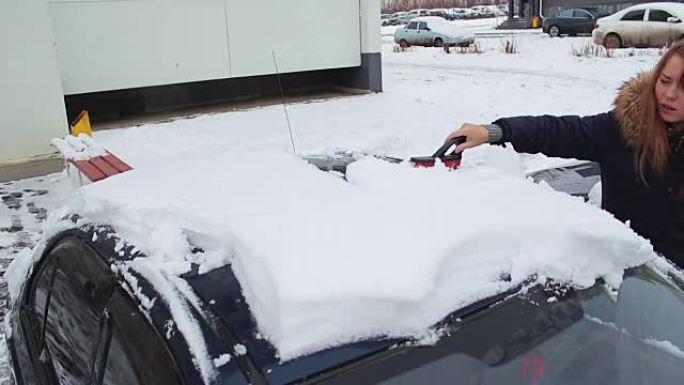 一个女孩从雪中清理汽车