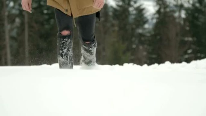 冬天，男人的腿穿着破旧的牛仔裤在森林附近的雪地里行走