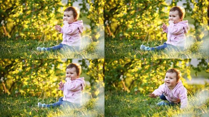小漂亮的女婴坐在太阳卫星公园的绿草地上。