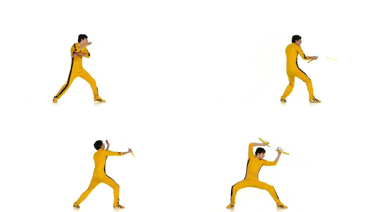 穿着黄色西装的男子训练空手道和熟练地旋转双节棍