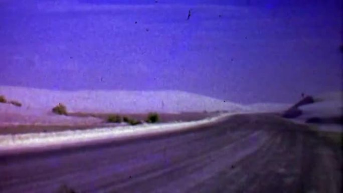 1957: 冬季飘雪吹过贫瘠的道路景观。