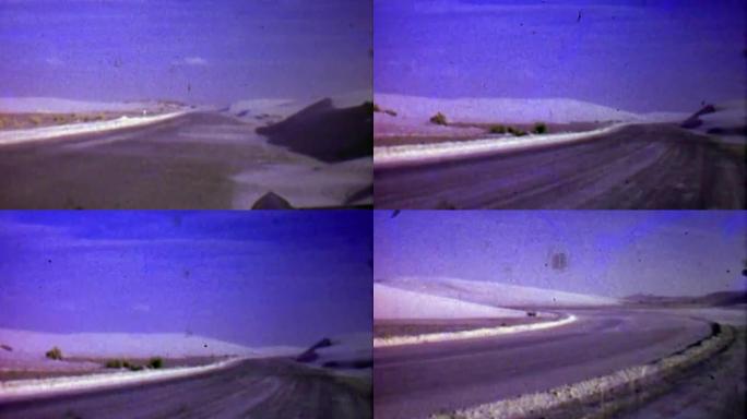 1957: 冬季飘雪吹过贫瘠的道路景观。