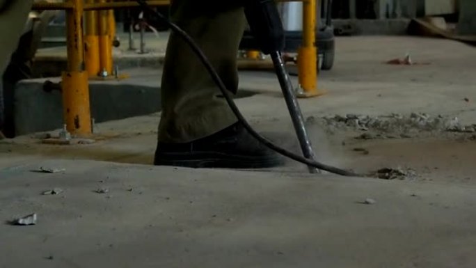 工业工人在施工现场用电动冲击锤钻混凝土。