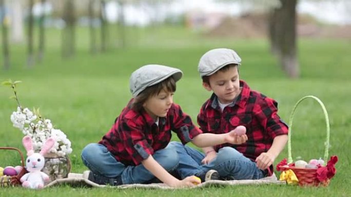 两个孩子，男孩兄弟，在公园里玩复活节彩蛋，美丽的春天盛开的花园