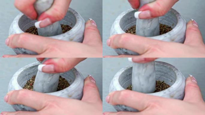 女性的手在研钵里切碎胡椒。调味黑胡椒粉