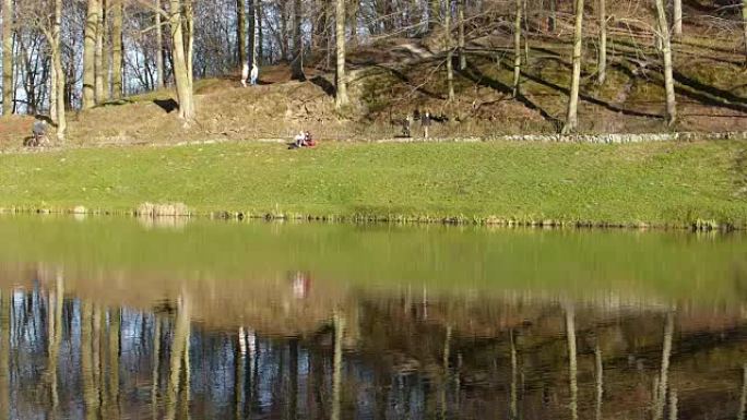 人们在池塘旁的公园里放松