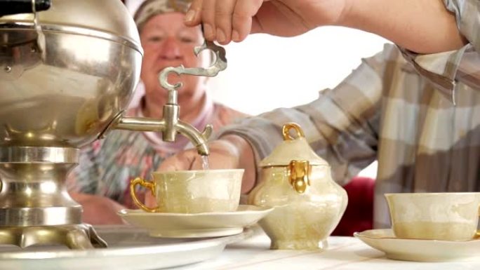 一对老年夫妇用老式的俄罗斯水壶茶壶准备茶。一个留着胡子的男人为妻子倒茶