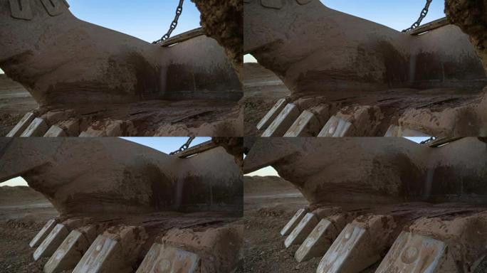手持倾斜的特写镜头拖曳挖掘机斗15立方米与巨大的链条站在采石场的一边与日落的蓝天。