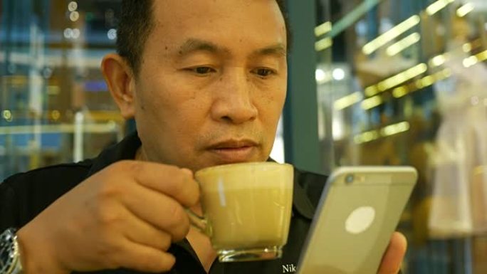 咖啡店里使用手机的成熟男人