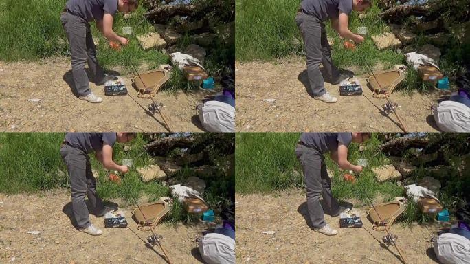 一个戴眼镜的人将钓鱼设备固定在钓鱼竿上。渔具。带钓鱼设备的塑料盒。库班河