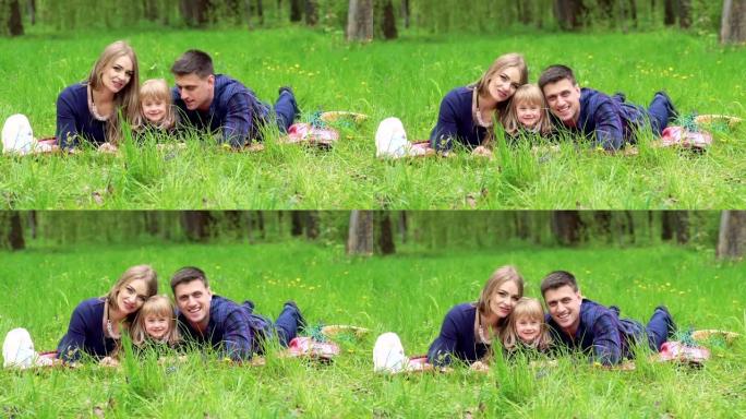 有女婴的家庭在公园的草地上休息。慢慢地