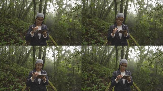 亚洲妇女在雨林中旅行使用数字平板电脑拍照