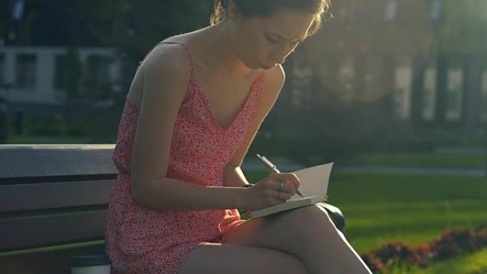 女孩在日落时在阳光下做笔记，在日记中写下她对未来的希望和梦想，制定计划。计划要做