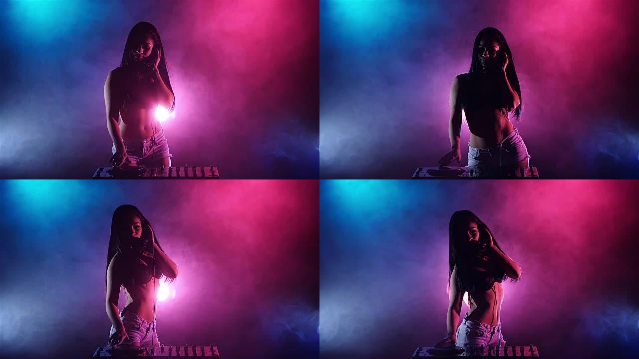 女孩DJ开始跳舞蓝色粉红色的灯光和大量的烟雾。慢动作。剪影