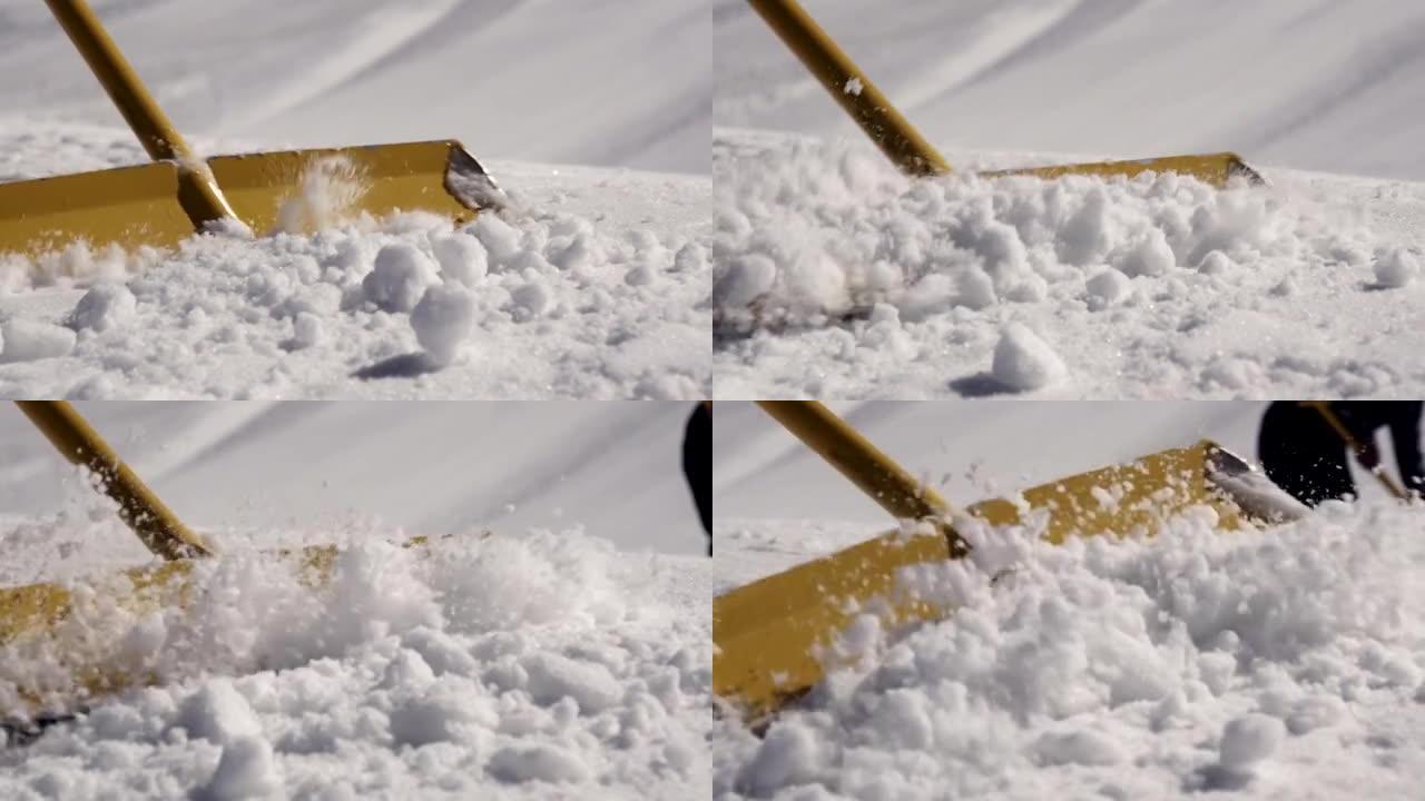男子在滑雪胜地用铲子扫雪。晴天。山。喷涂。雪堆