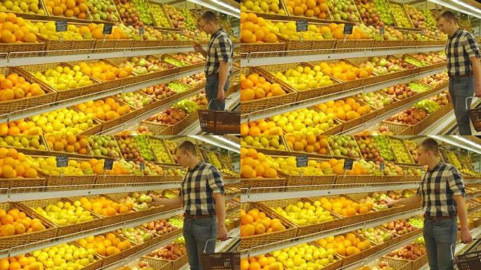 男子在杂货店农产品部门选择新鲜的红苹果并闻起来。带购物篮的年轻帅哥正在超市挑选苹果。