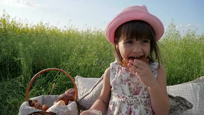 儿童野餐自然，可爱的小女孩肖像吃百吉饼，面团产品，日落时喝牛奶，家庭野餐的孩子