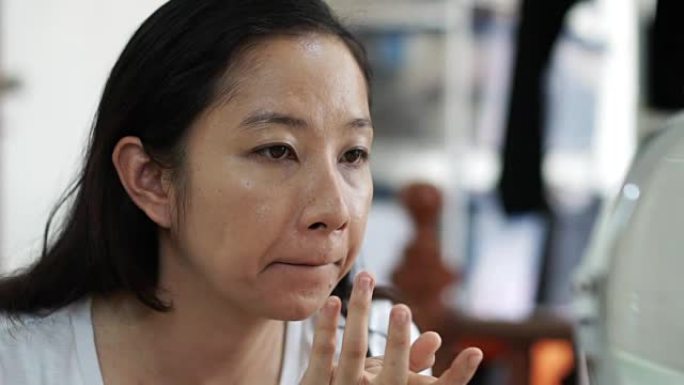 亚洲女性在慢动作化妆前先在脸上涂抹粉底