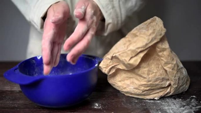 人类的手用面糊在碗上方甩掉面粉