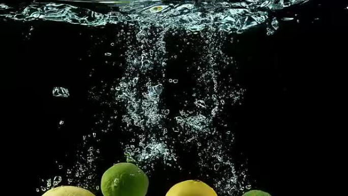 黄色和绿色柠檬，柑橘柠檬汁，柑橘金叶，黑色背景下落水的水果，慢动作4K