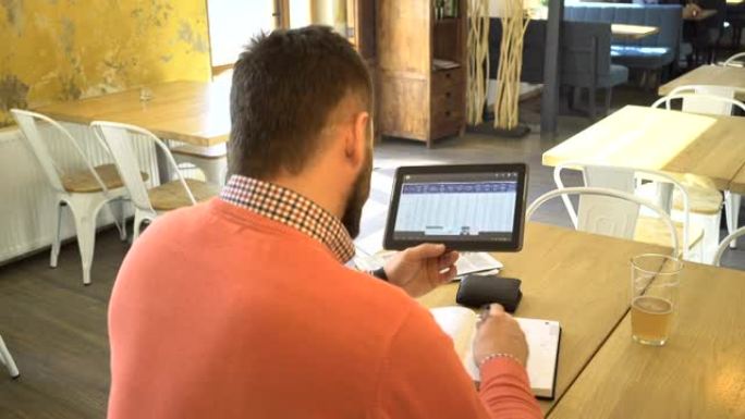 在咖啡馆里，在平板电脑上分析数据和写笔记的人，离镜头很近
