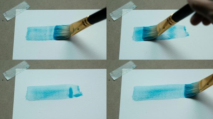 艺术家的特写镜头用画笔在水彩纸上200 GSM的水彩画蓝色矩形。