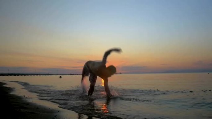 运动员在日落时在海滩上做杂技表演