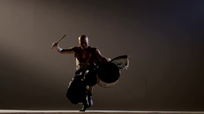 萨满在灰色背景上用鼓跳舞。亚洲民族舞蹈。在慢动作的红色史诗巨龙电影相机上拍摄。