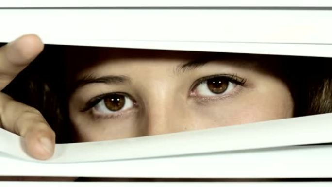 封闭的威尼斯百叶窗打开，显示出美丽的棕色眼睛的年轻女子，她看起来很严肃，然后眨眼。