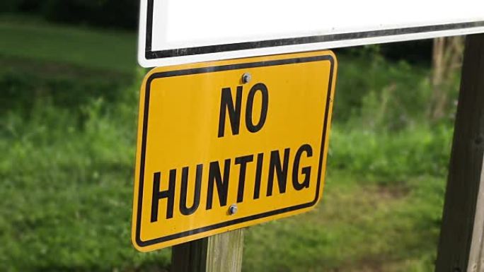 女子走过一个禁止狩猎的标志在州立公园