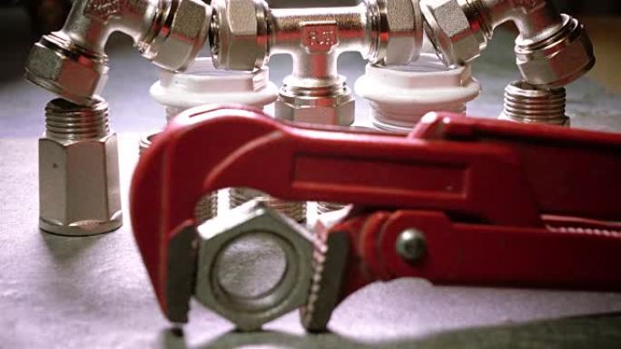 红色金属制品可调扳手，用于卫生工程，背景是水切断和供水连接截止阀