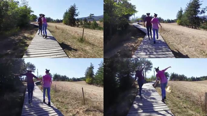 两个十几岁的女孩在山木人行道上徒步旅行，跑步，跳跃