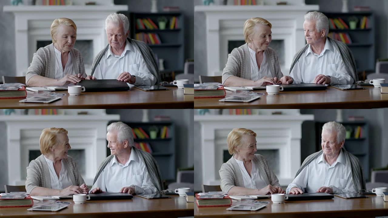 快乐的老年男女使用电脑。他们合上它，互相看着对方