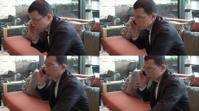 4k: 年轻的亚洲男子在咖啡馆工作并在手机上聊天