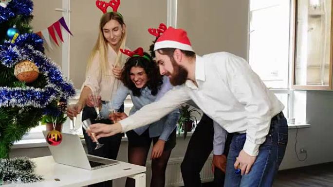 圣诞老人帽子快乐团队的侧视图在公司办公室聚会上进行电话会议和用起泡酒碰杯。办公室里的企业新年派对。国