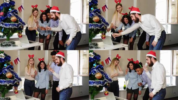 圣诞老人帽子快乐团队的侧视图在公司办公室聚会上进行电话会议和用起泡酒碰杯。办公室里的企业新年派对。国