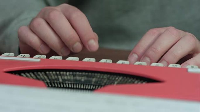 男性的手在红色打字机上打字