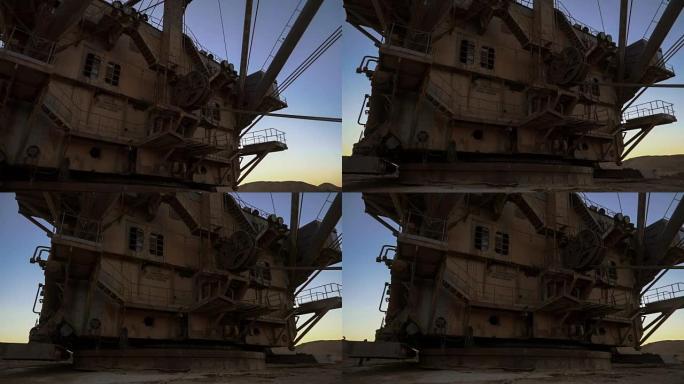 PAN拍摄拖网超重型挖掘机基地和机舱，夕阳下，蓝天下，站在采石场边。