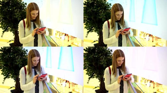 商场里有智能手机的年轻美女。浏览互联网，与朋友交流