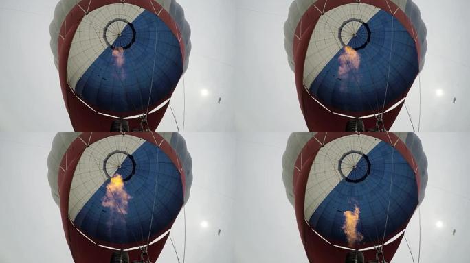 热气球。燃烧器将火焰引导到天空中的背景氦气飞艇上的信封中