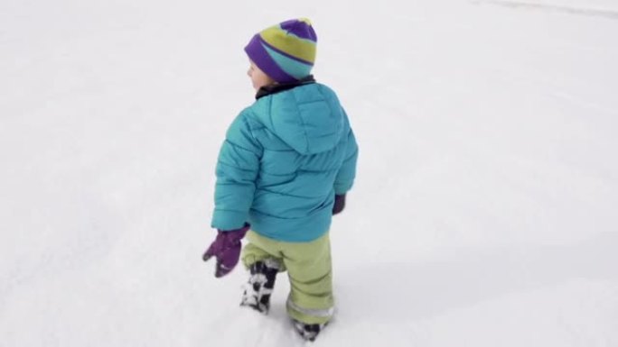 慢动作: 小男孩在积雪覆盖的田野上奔跑