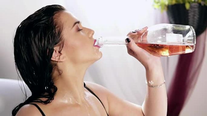 漂亮的年轻女子在装满牛奶和鲜花的热水浴缸里洗澡，放松地从瓶子里喝香槟。慢动作镜头