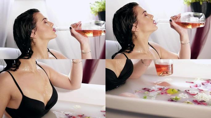 漂亮的年轻女子在装满牛奶和鲜花的热水浴缸里洗澡，放松地从瓶子里喝香槟。慢动作镜头