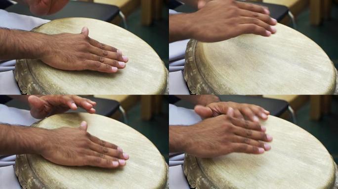 特写男人的手在皮肤覆盖的邦戈手鼓上击鼓。慢速MO 1