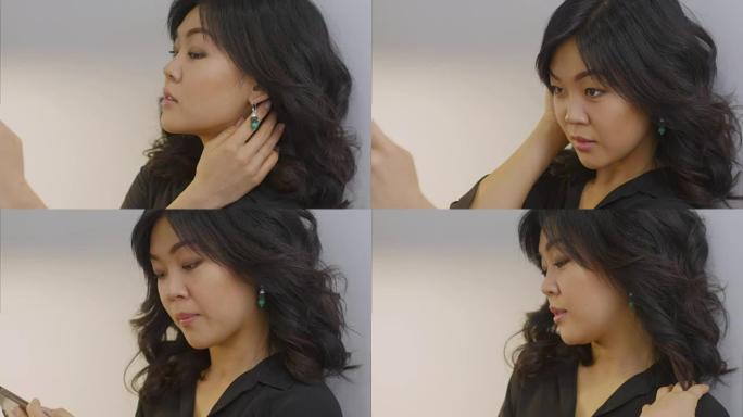 年轻的亚洲女性使用智能手机在新设计的耳环中自拍