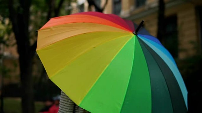 女性手中的开放式旋转彩色彩虹伞的特写视图。慢动作镜头