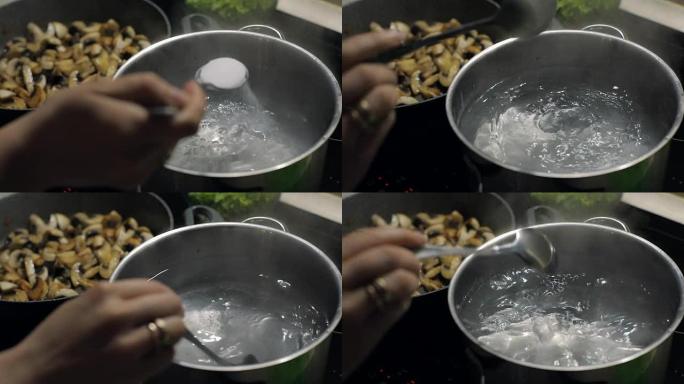 在锅里的沸水中加盐。背景是炒蘑菇。慢动作