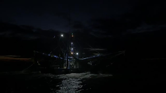 黎明时分用网捕鱼的虾拖网渔船的背后