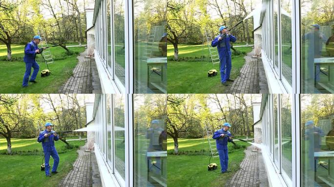 男子清洗温室窗户，水射流反射在玻璃上