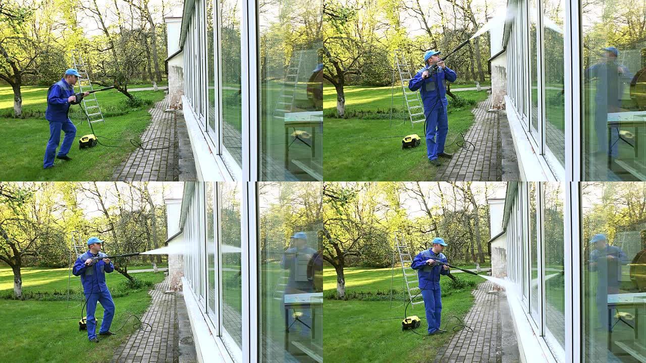 男子清洗温室窗户，水射流反射在玻璃上